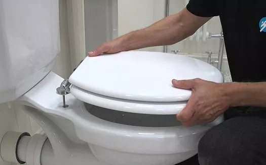 plumber showing how to replace toilet seat