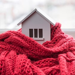 a house wrapped in a blanket depicting the coziness you will feel with your winter boiler preparation covered